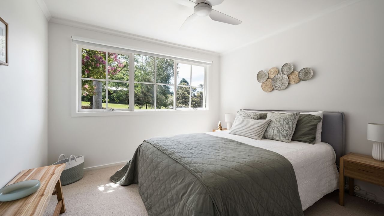 Spacious room with queen bed, built in wardrobe, and bedside tables with lamps. 