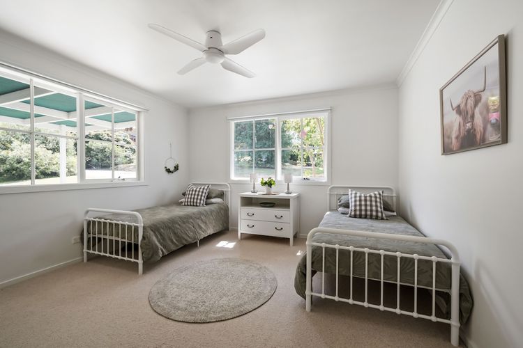 Bedroom with built in wardrobe, ceiling fan, bedside table with lamps, 2 single beds and lush carpets. 
