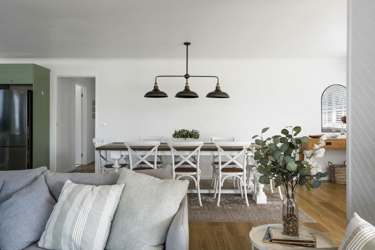 A sunlit dining area equipped with an eight-seater table, and overhead lights. 