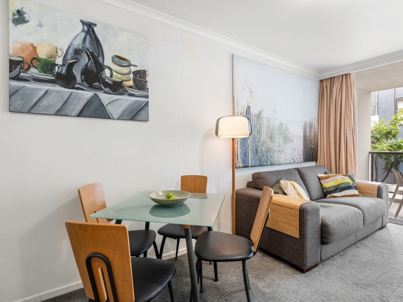 Modern Comfort with a Touch of Art – Relax in this stylish living space featuring contemporary décor and a cozy sofa.