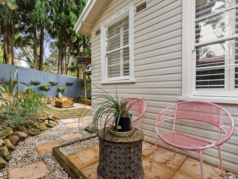 Enjoy outdoor dining in the serene backyard with lush greenery surrounding you.