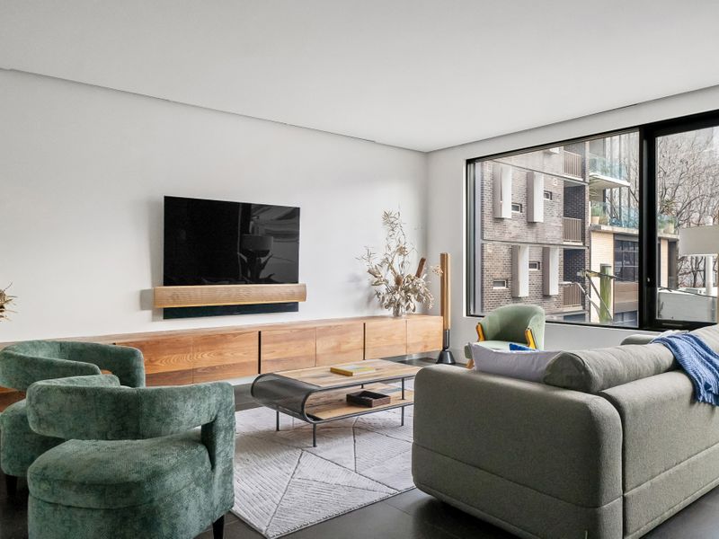 This stylish and modern living room features comfortable seating, a sleek entertainment setup, and large windows offering a bright and inviting atmosphere.