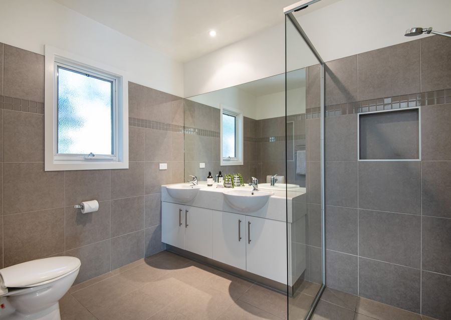 Main bathroom with walk in shower, double vanity and toilet